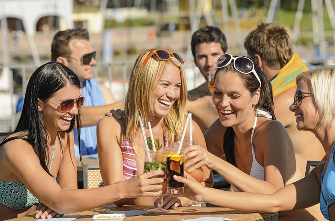 Beautiful women in bikinis toasting with cocktails at beach