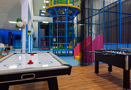 Vnit n hern  prostor s air hockey stolem, stoln m fotbalem a barevn m prol za kov m za  zen m.  Popis generovan  AI